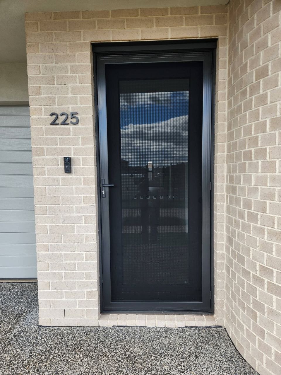 Black security door at house number 225, modern brick home